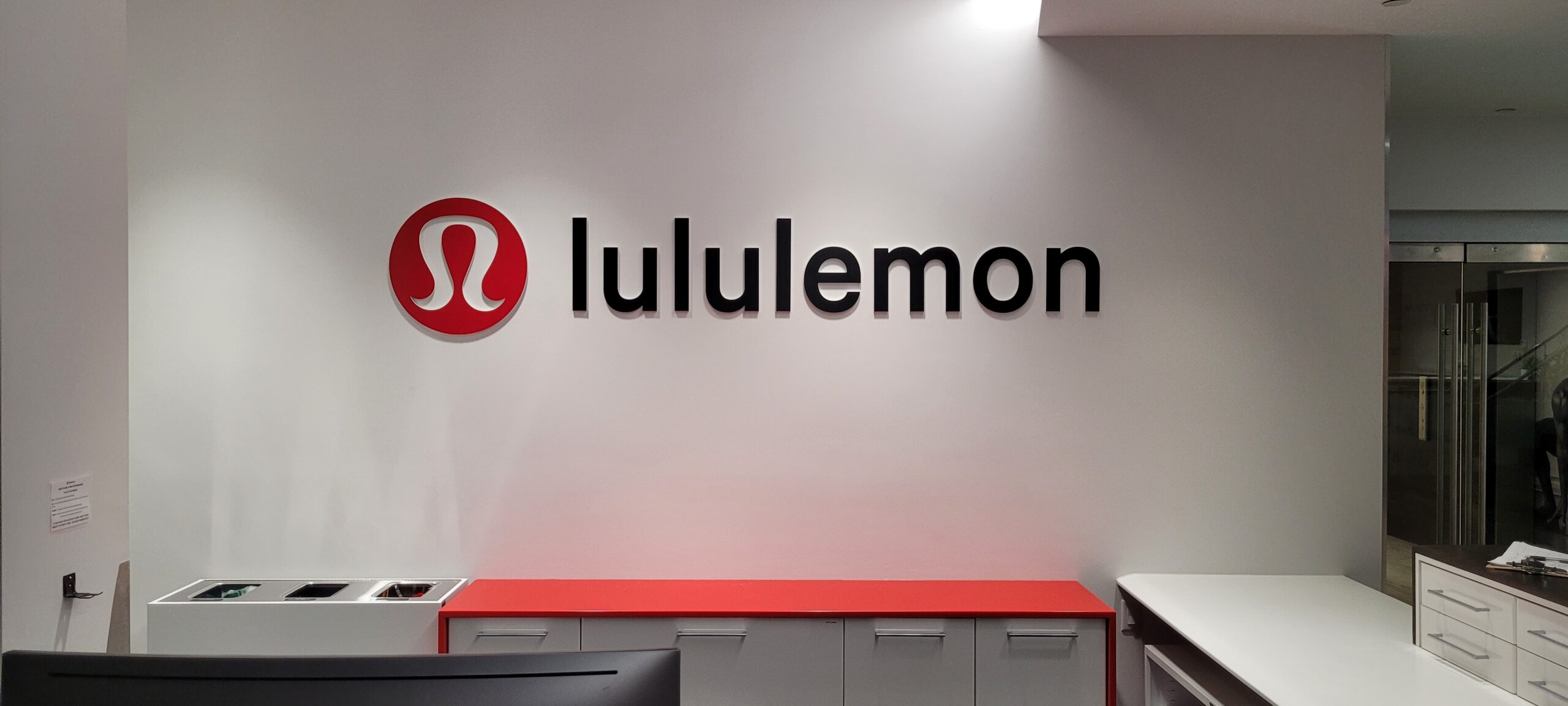 Lululemon logo on modern white wall interior with red counter