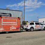 SpeedPro Medicine Hat installing vehicle wrap on work truck; branded fleet vehicles parked in Medicine Hat.