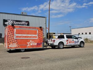 SpeedPro Medicine Hat installing vehicle wrap on work truck; branded fleet vehicles parked in Medicine Hat.