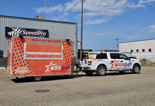 SpeedPro Medicine Hat installing vehicle wrap on work truck; branded fleet vehicles parked in Medicine Hat.